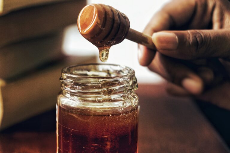 Jar of raw Kashmiri honey with wooden honey dipper